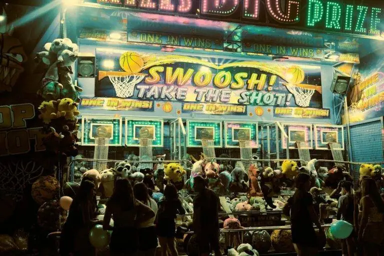 A lively carnival booth at night in Arlington Heights with people enjoying games.