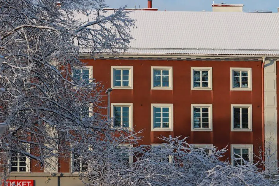 A stunning winter scene of a red building framed by frosted tree branches.
